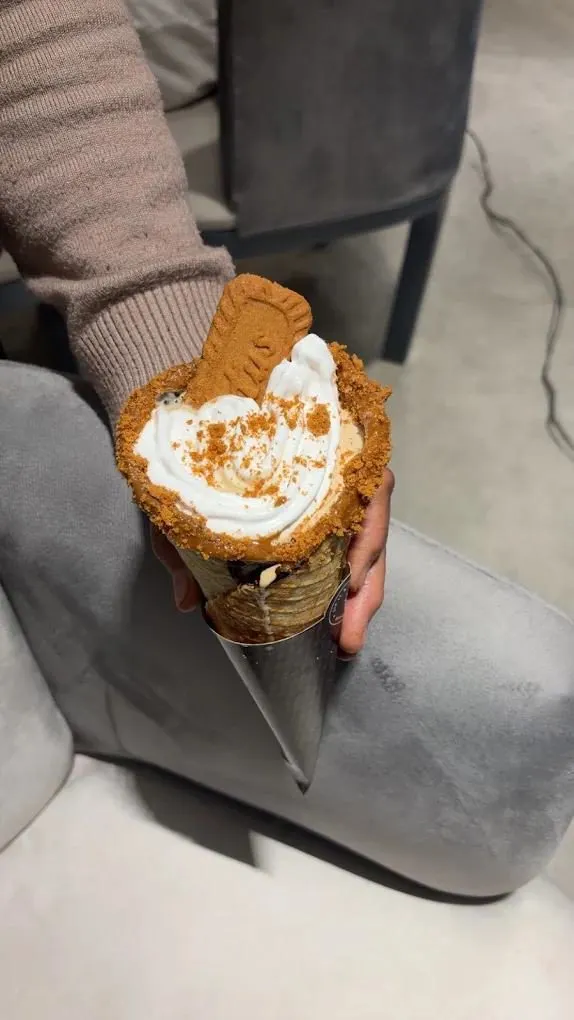 Hand holding a waffle cone with whipped cream